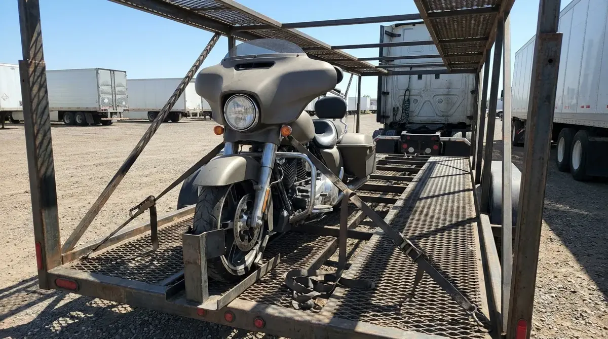 A touring motorcycle secured in a wheel chock on the deck of an open car carrier